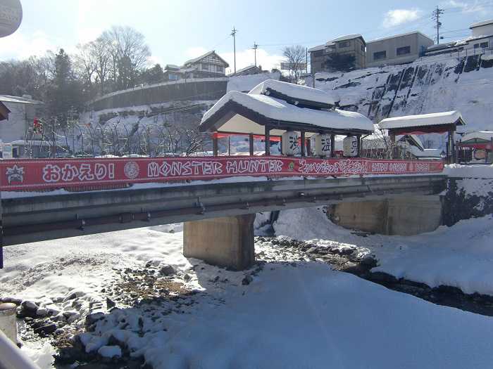 Puente cercano al pueblo de Shibu Onsen. Cartel colgado del evento de Monster Hunter